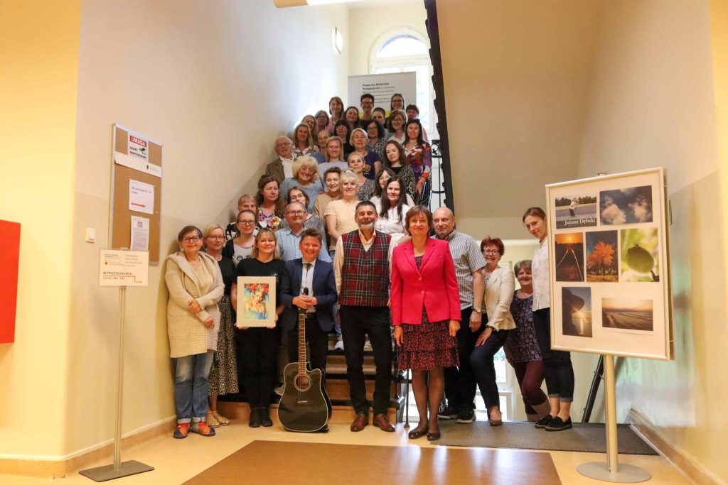 uczestnicy wernisażu wraz z artystami ustawieni do grupowego zdjęcia na schodach biblioteki