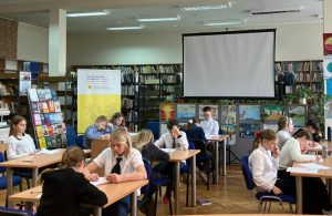 uczniowie piszący test konkursowy w bibliotece w ramach konkursu "Z książką na ty"