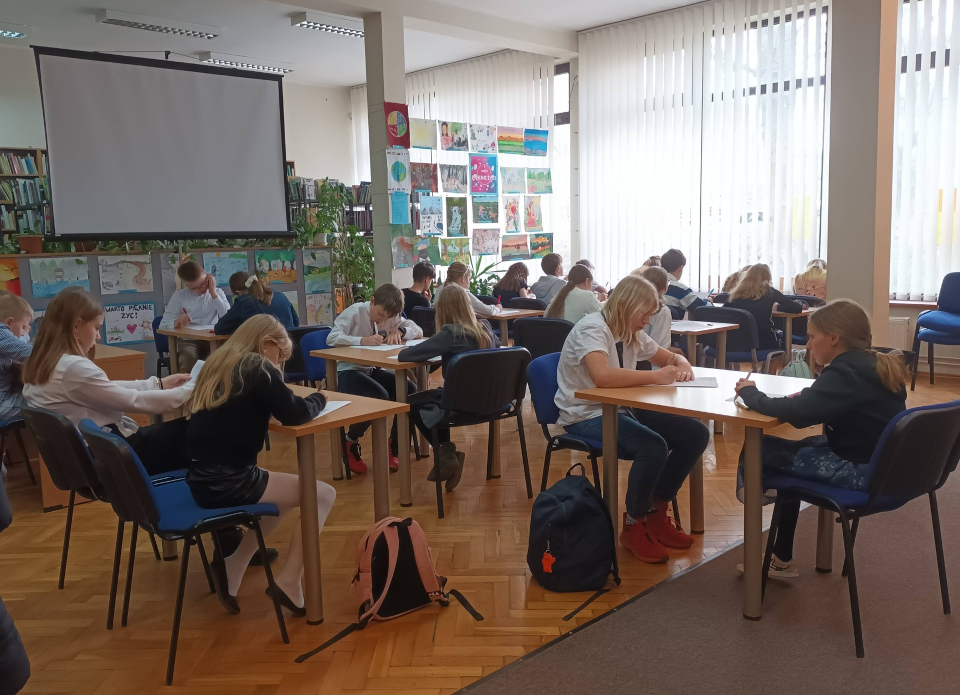 uczniowie piszący test konkursowy w bibliotece w ramach konkursu "Z książką na ty"