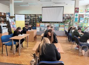 uczniowie piszący test konkursowy w bibliotece w ramach konkursu "Z książką na ty"